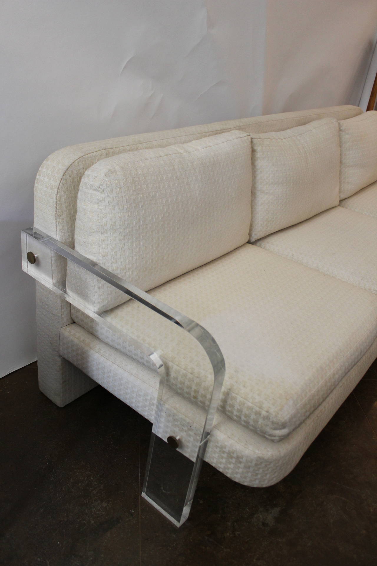 Upholstered cream sofa with acrylic arms and brass hardware, Mid-Century. Smaller loveseat also available, sold separately.