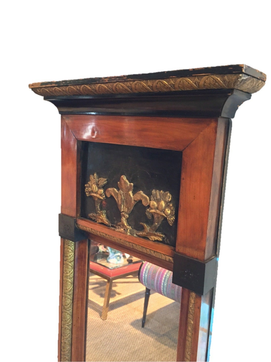 Tall and narrow walnut and ebonized wood framed mirror with gilt hand-carved detail border and cornucopia detail at top.