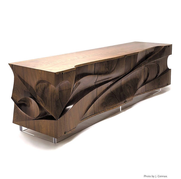 This dynamic cabinet or sculpture is made from beautiful exotic hardwood. Deep carved wood exterior and sides form undulating lines, sunken nooks and crevices to create a formidable facade. The unit rests on a 4