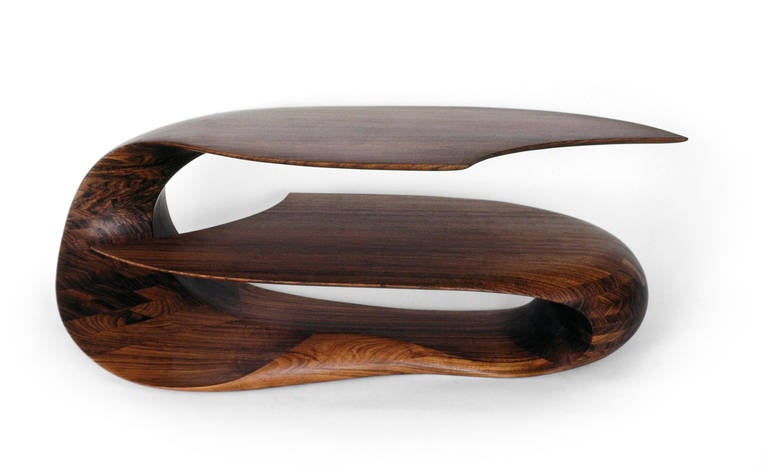 This double-finned enfolding coffee table is carved from solid exotic hardwood . Its undulating, layered shape adds storage and functionality to a timeless piece.

We specialize in custom commissions.
Custom materials, finishes and dimensions