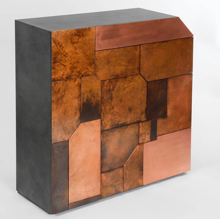 The Elementi cabinet is a monolithic, rough and challenging piece of sculptural furniture. The copper mosaic panels have been aged and treated to give them different textures and luster. Disguised behind the panels are two cupboards and five drawers.