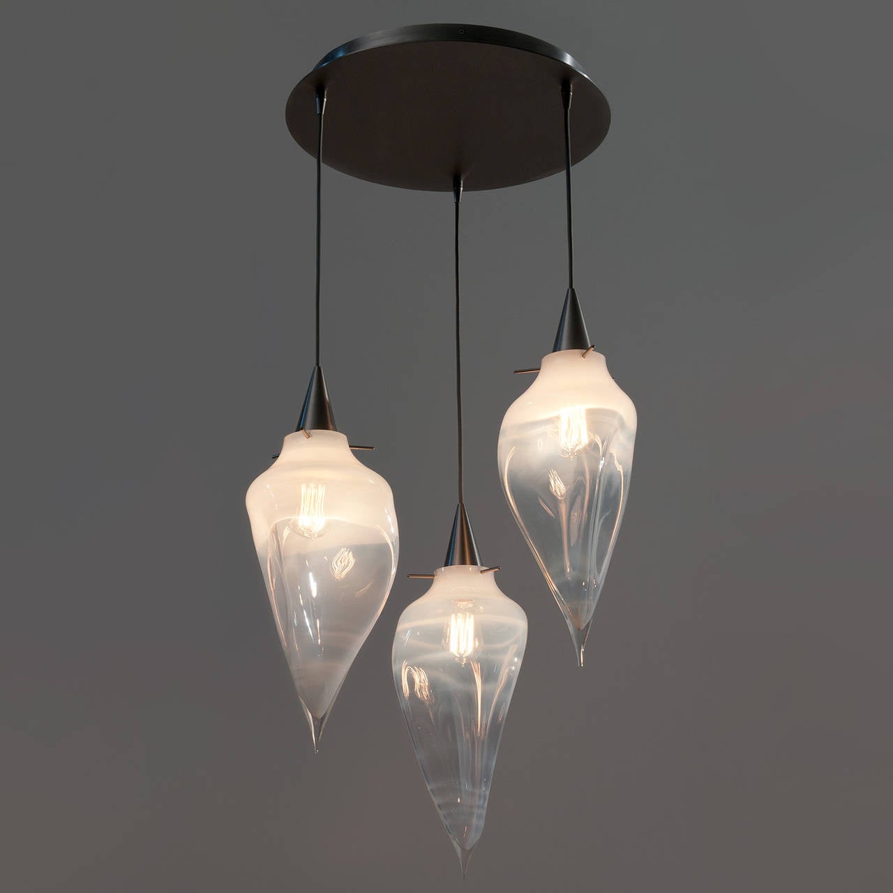The Rock Pendants feature undulating forms that move like molten glass. This chandelier groups three handblown pendants on a central chandelier canopy.

We specialize in custom commissions.
Custom materials, finishes and dimensions available.