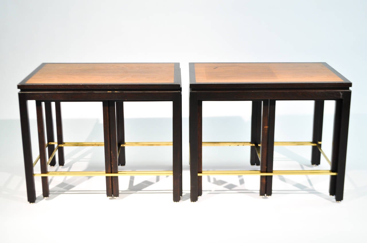 A rare pair of nesting tables by Edward Wormley for Dunbar. Each set features three tables, one larger and two matching end tables. The larger piece is channeled to hold the two smaller beneath. Each elegant piece features brass stretchers under a