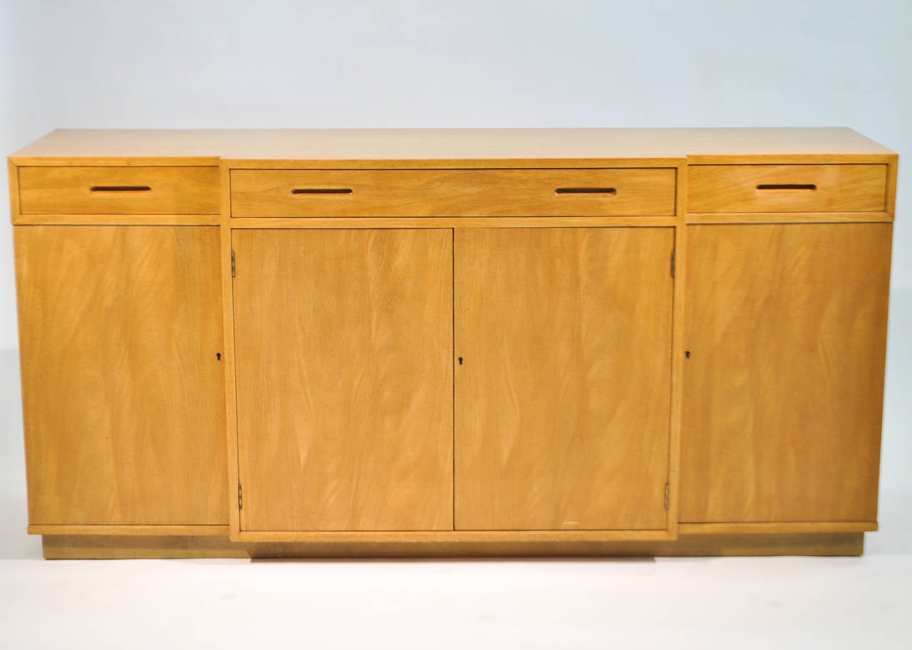 A beautiful bleached mahogany sideboard by Edward Wormley for Dunbar, part of his New World collection. This piece features three drawers with compartments below. A central long drawer is flanked by two smaller, the smaller two with felt lined