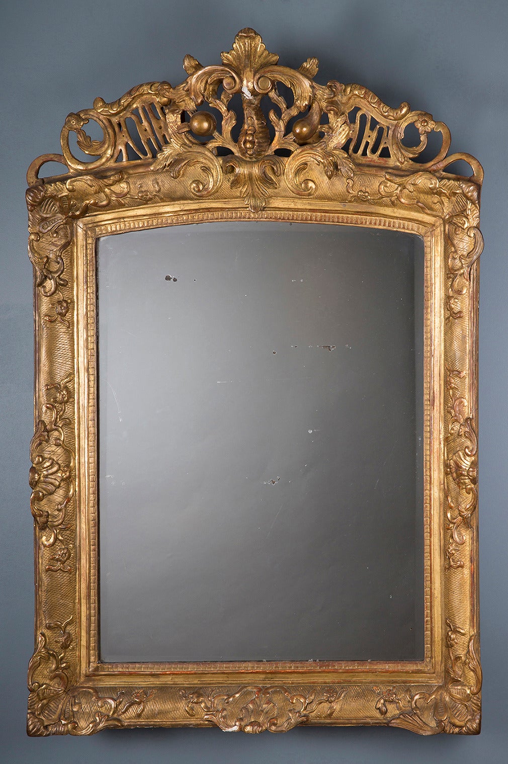 Mirror adorned with floral, foliate patterns and pomegranate.

Its gilding is original.

Parisian work from the Regency period.

Dimensions : 117 x 81 cm.