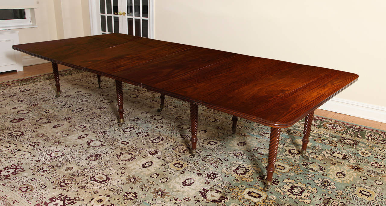 Lively and rich mahogany dining table incorporating three leaves (dimension here is for fully extended). The top with characteristically Irish thick molded edge, raised on elegant tapering, spiral-fluted legs ending in brass caps and casters. This