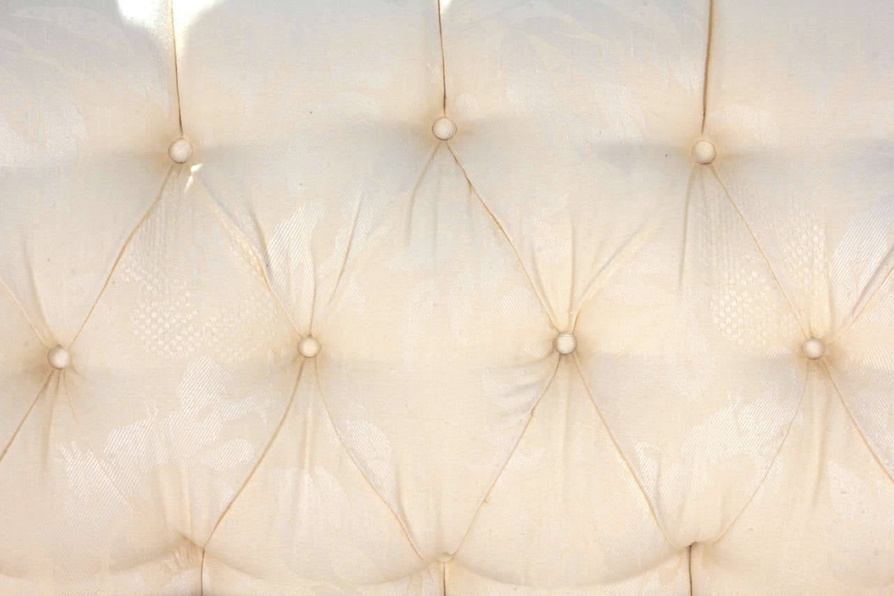 Custom-made long sofa covered in cream damask.