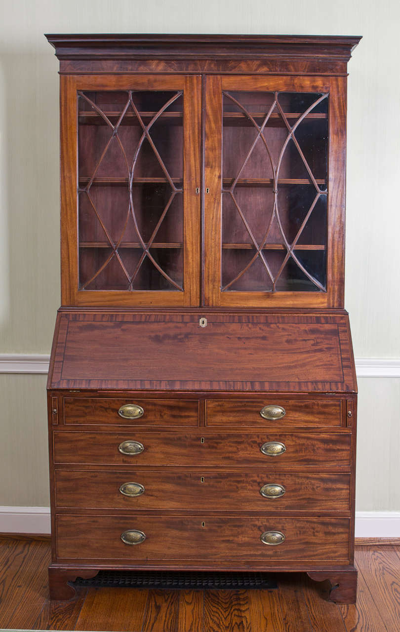 Rich, warm color and nice figure to timber; the upper section with adjustable shelves; the lower section with slanted fall front opening to a leather-lined writing surface and arrangements of drawers and pigeonholes; fitted with two short over three