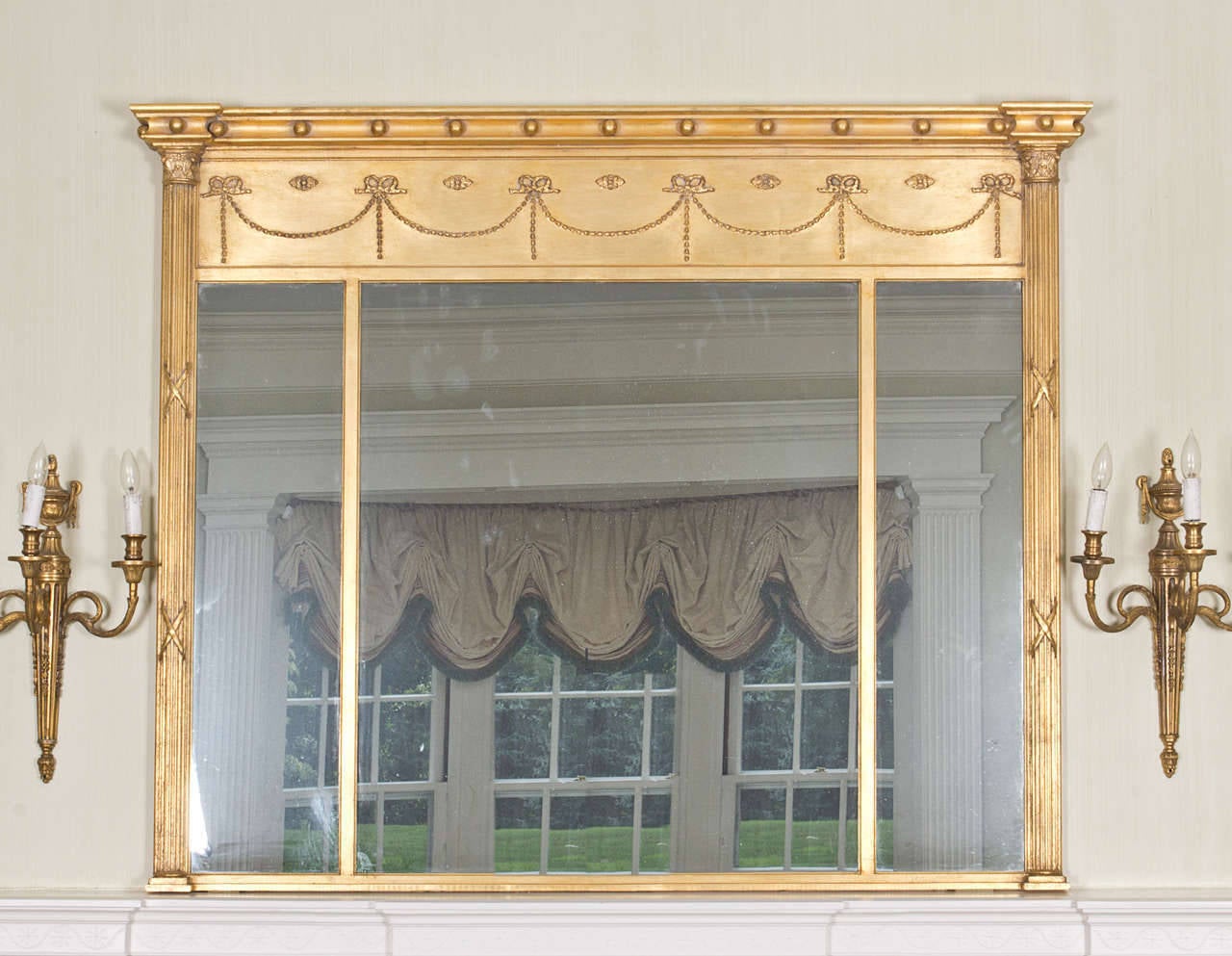 Neoclassical giltwood overmantel mirror of reverse breakfront form; with ribbon-tied garland decoration.