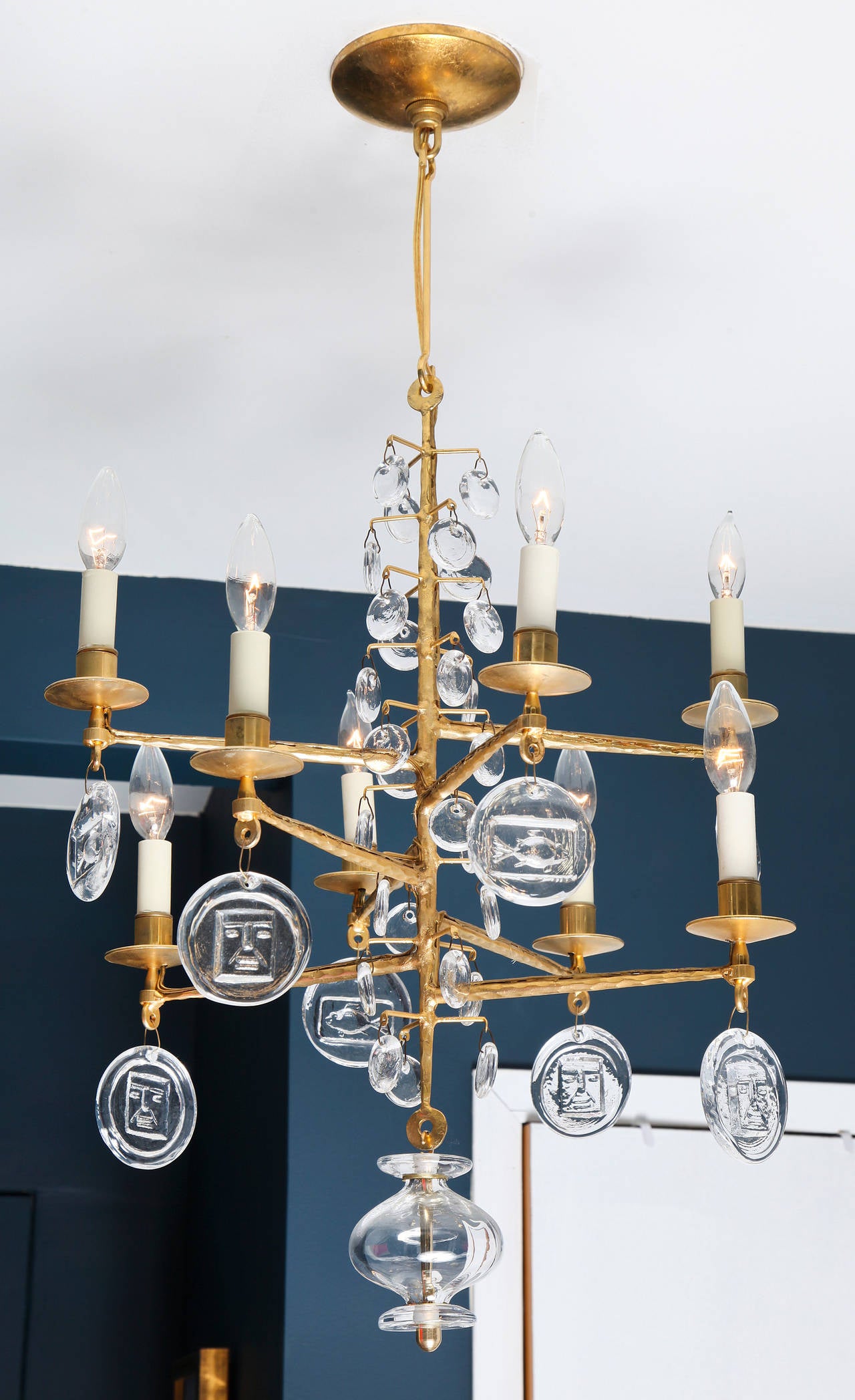 With eight candle arms arranged at staggered heights and hung with glass pendants molded with a face motif, a Hoglund signature. Electrified.

Erik Hoglund (1932-98) began working at the Boda glassworks at the age of 21 immediately following art