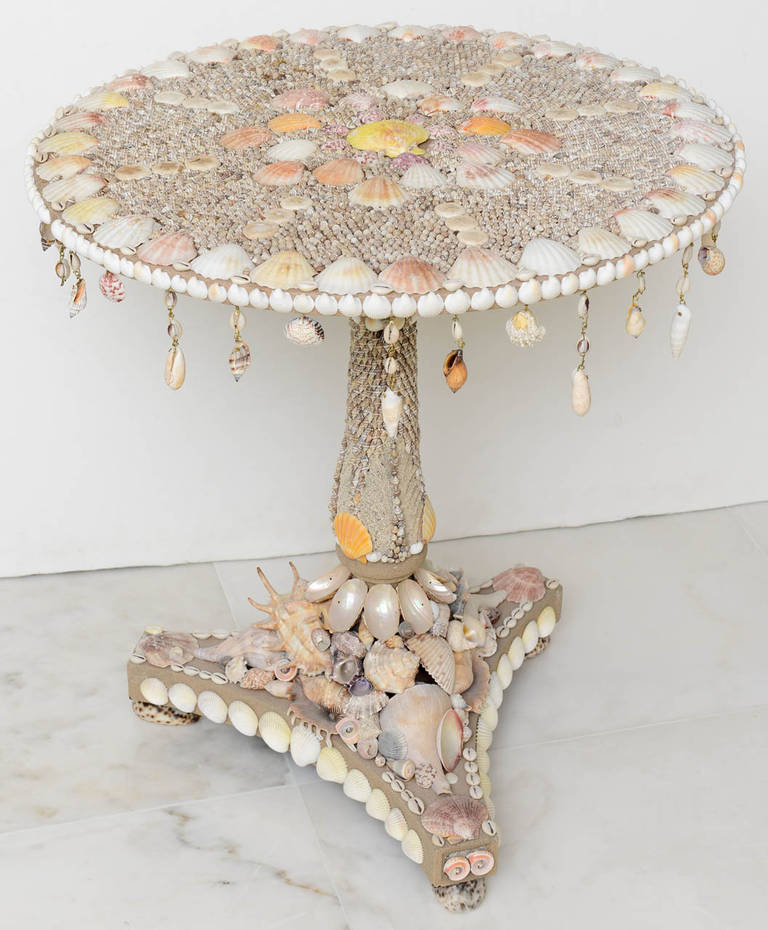 A fabulous example of coquillage! The Regency style tripod table elaborately applied with seashells, including shell pendants hung from the top edge; on a turned columnar support with tripartite base and shell feet.