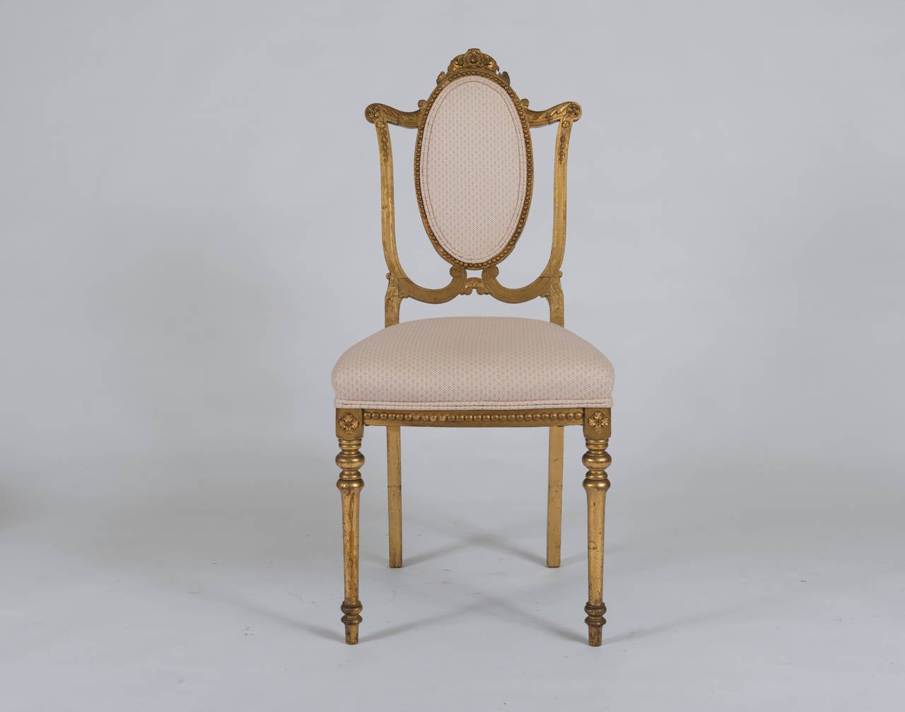 With oval upholstered back and seat; the giltwood frame with floral and foliate carved decoration.
