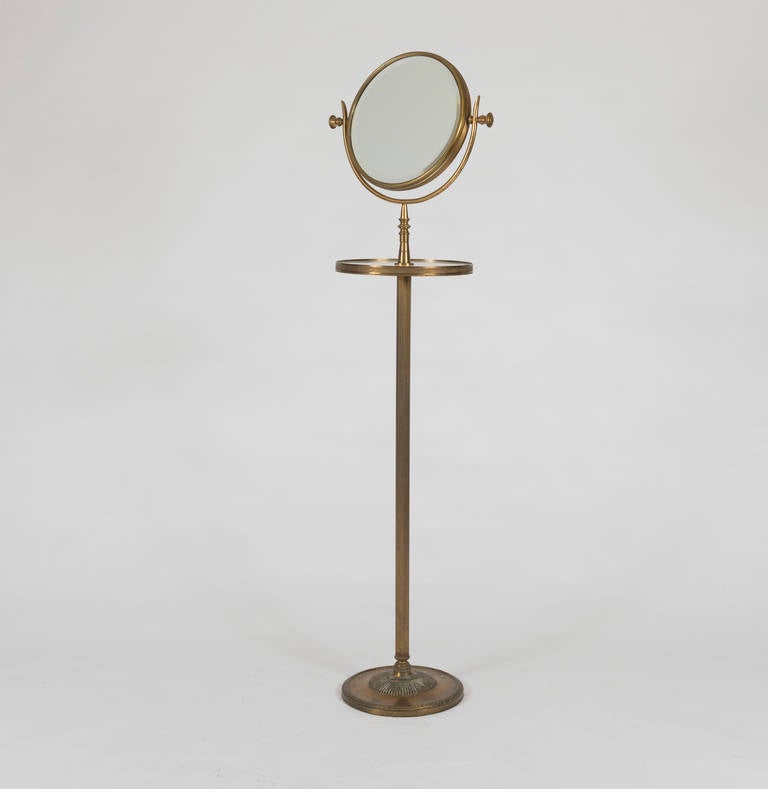 The round mirror on an adjustable support with marble-inset shelf.