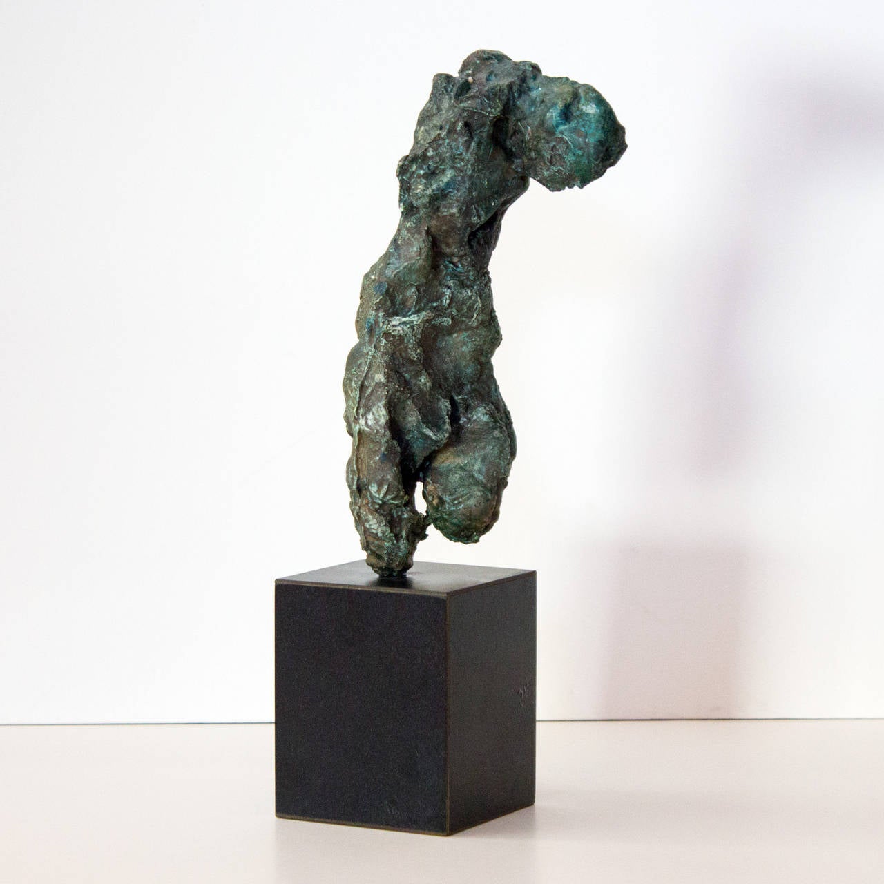 A small plaster sculpture of a partial human figure by New York artist Auguste Garufi. Composed of plaster and pigment and mounted on a black base.