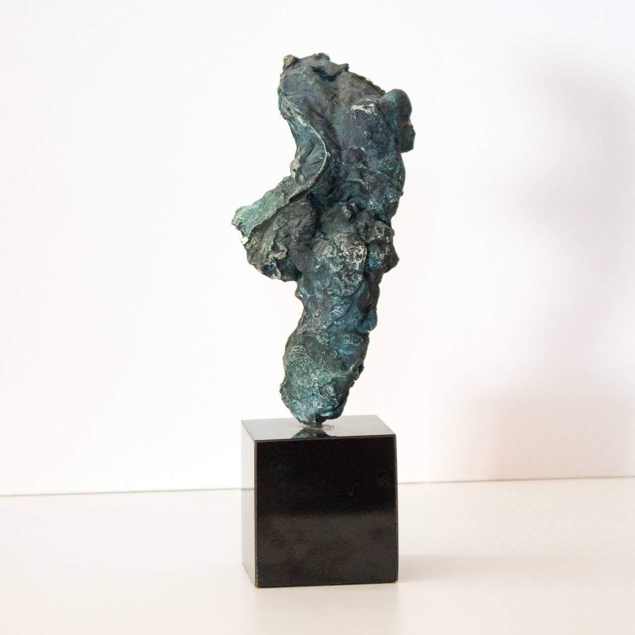 A small plaster sculpture of a partial male torso by New York artist Auguste Garufi. Composed of plaster and pigment and mounted on a black base.
