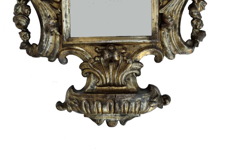 An 18th century antique silver-leafed Italian mirror with deep carvings and a shell crest.