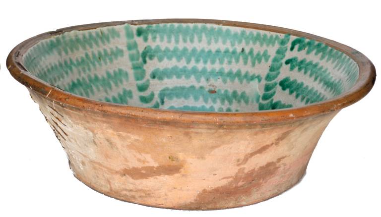 A large antique stoneware Lebrillo bowl from Granada; with a green  glaze over a cream background.  Verso with  old staple repairs typical of these  bowls.