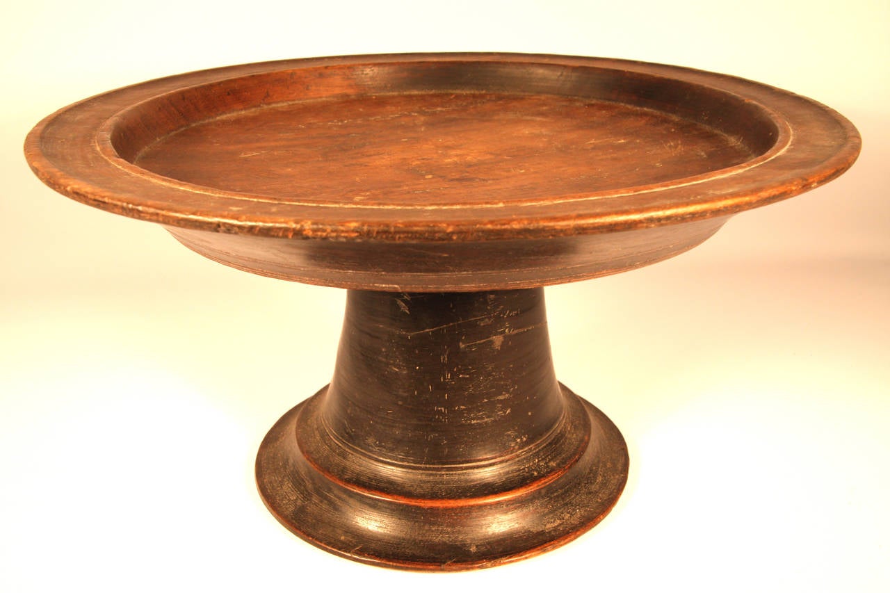 Late 18th Century, American oversize painted walnut compote having original black paint. The platter interior with dark, natural “scrubbed” patina. Carved from a single piece. The double rimmed dish top, flared incised outer body above a flared,