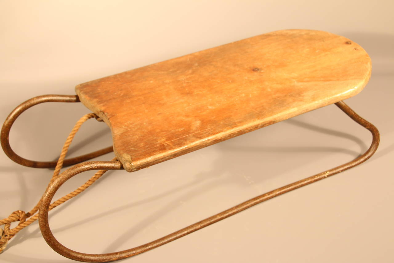 19th century American pine and iron child's sled in original condition with rope pull, iron runners, and wood support.  Nice diminutive size with delicately curved runners on front and back.  25