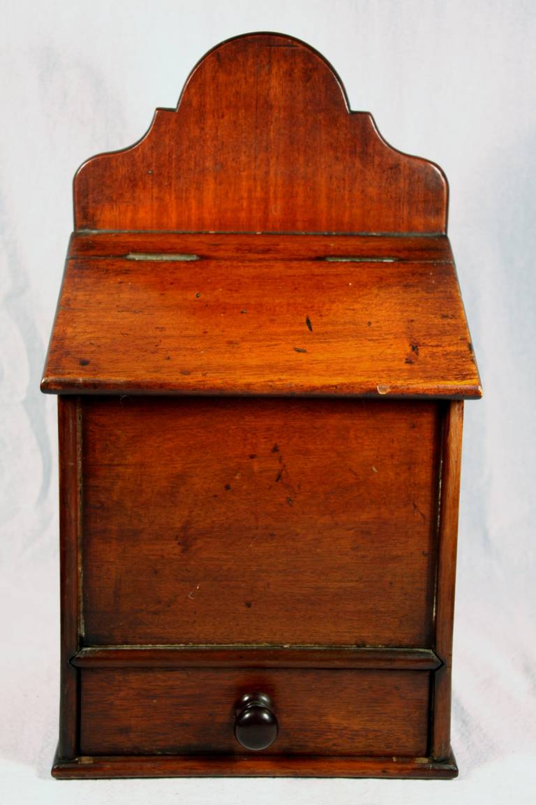 Mid 19th century walnut salt box with lift top and lower drawer in very good condition.  Scrolled and carved top with tapered lid atop salt box.