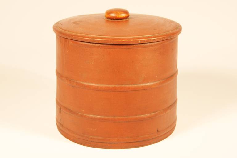 First quarter 19th century, New England storage container with lid.  The slightly tapering body with integral raised band design, the fitted lid with applied mushroom cap.  Carved from one piece of wood with inset bottom.  Finely tuned with nice dry