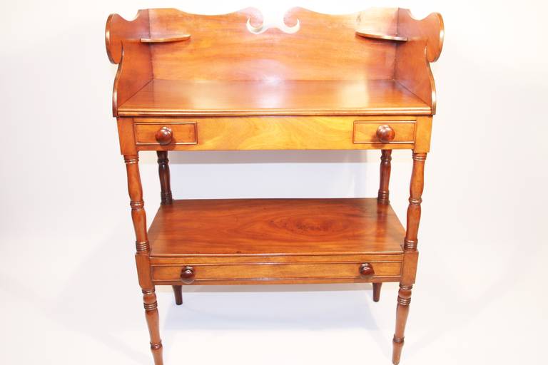 Sheraton Mahogany diminutive server or butler's table.  Top with carved back splash, delicately scrolled sides, and two candle shelves with two small drawers on each side.  Medial shelf with shallow drawer the length of the stand.  Sitting atop