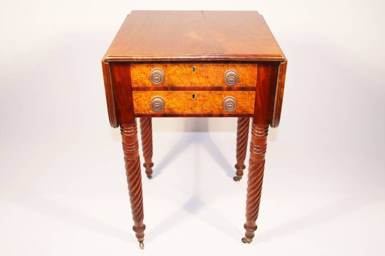 Sheraton mahogany work table with two birdseye maple drawers. Top has molded edge and two drop leaves, dovetail drawers fronted with birdseye maple and having brass Sheraton pulls, legs ring and spiral turned, retaining original cup castors.

New