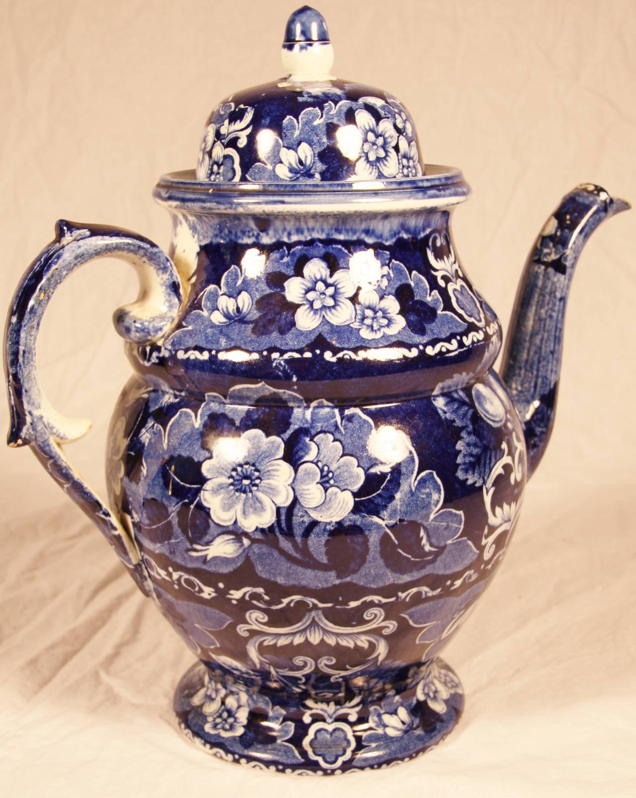 This early 19th century Staffordshire coffee pot is in excellent condition with a minor chip on the underside of the spout.  The coffee pot is a pearlware dark blue transfer-printed pot circa 1810-1820 with a floral design.