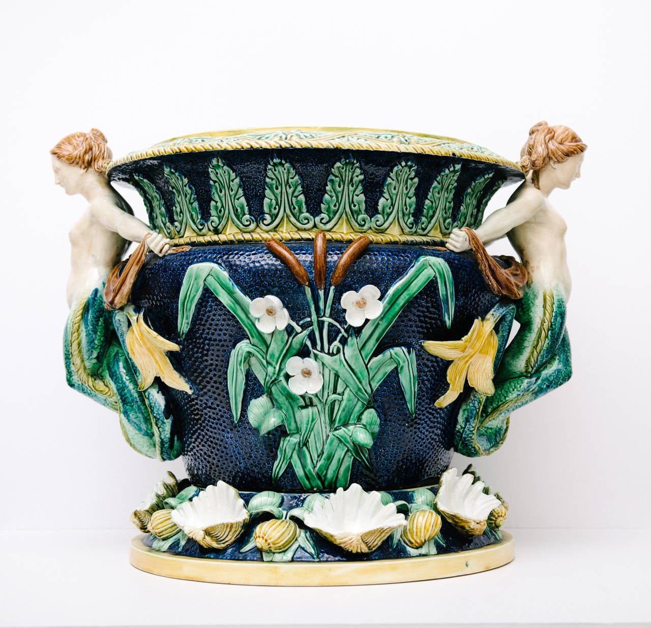 Monumental collector two piece mermaid majolica jardinaire beautifully embellished with clam shells, flora and fauna.