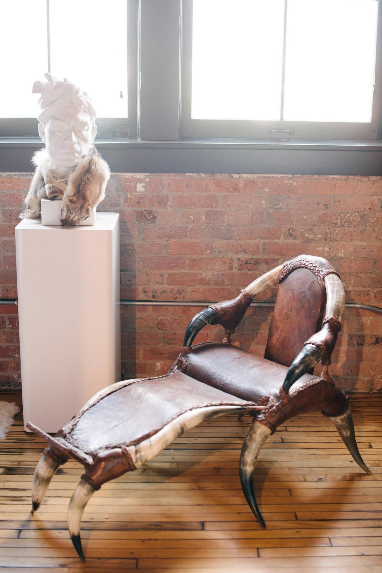 French leather and horn chair with detachable recliner piece and braided leather detail.