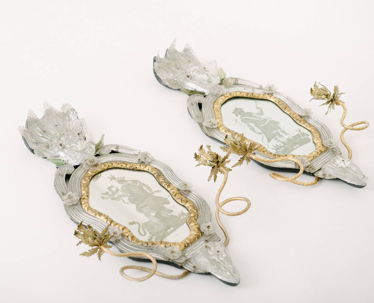 An exceptionally rare pair of 18th century Venetian etched mirror wall sconces. Each sconce features handblown glass to include extruded scrolls, flowers and an amazing monumental three-dimensional face under a crown of leaves. The etched mirrors