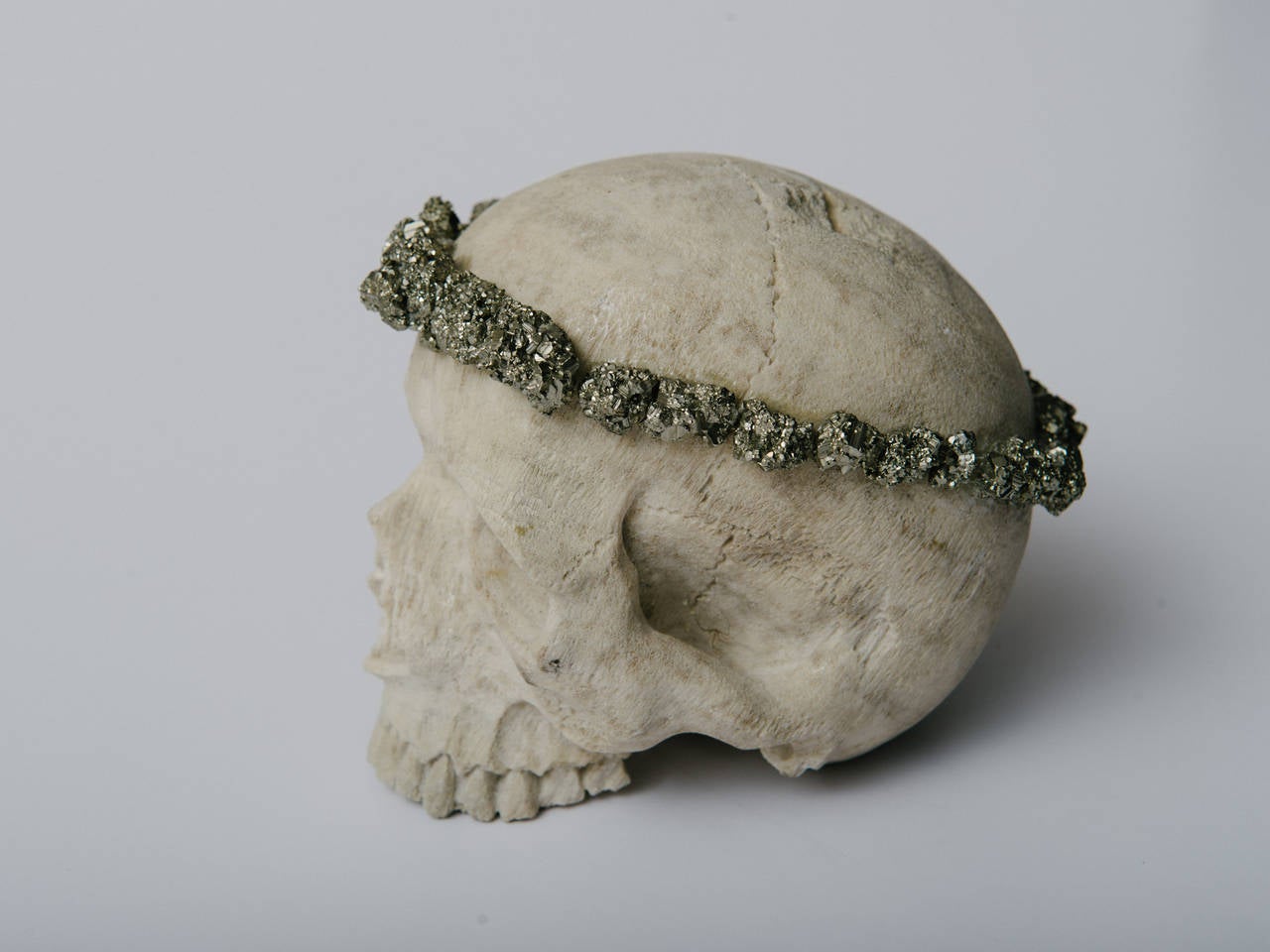 A beautifully hand-carved natural coral Memento Mori human skull adorned with a pyrite halo crown.