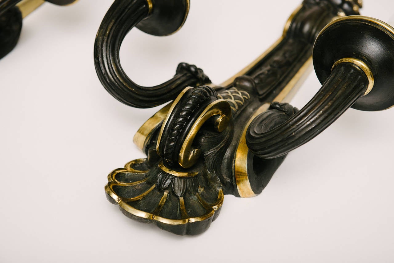 A stately pair of two-arm neoclassical black patinated bronze sconces with gilt detail.