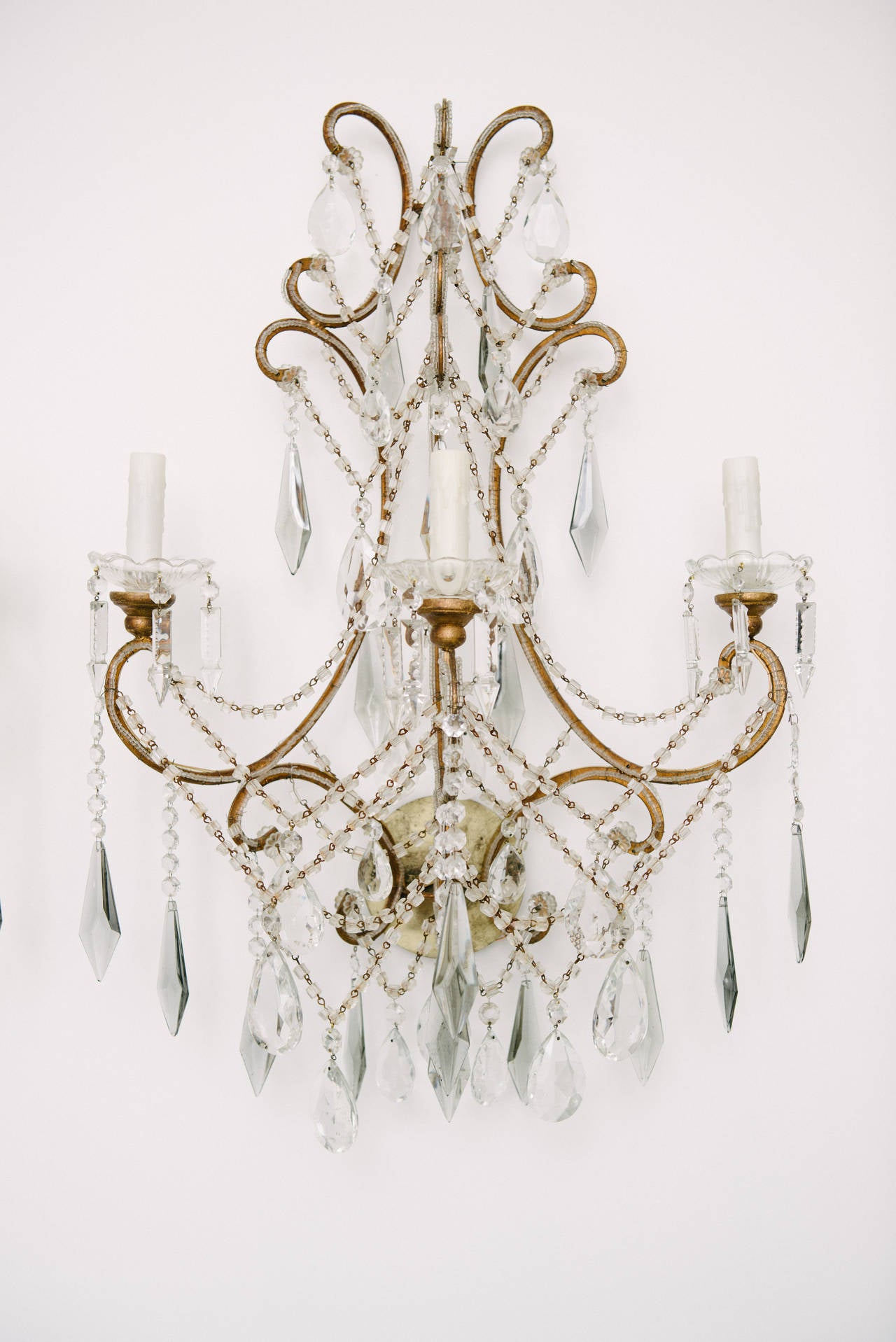 A beautiful pair of 1940s Italian sconces with lovely crystal prisms, beads, and cut bobeches. These airy newly wired sconces feature clear and smokey blue grey crystal prisms. Measures: 33” H.