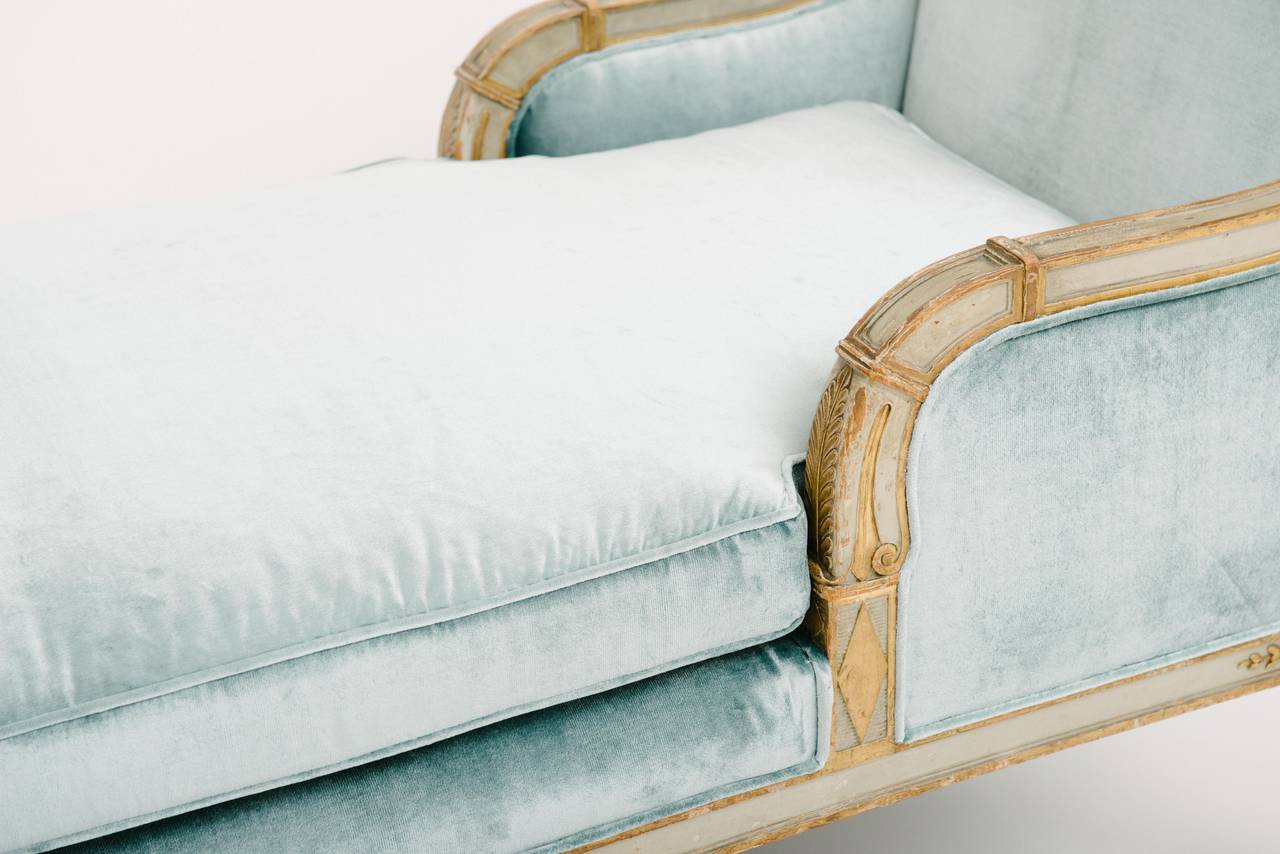 A lovely 19th Century Neoclassical style painted and parcel gilt chaise lounge newly upholstered in an icy blue silk velvet.