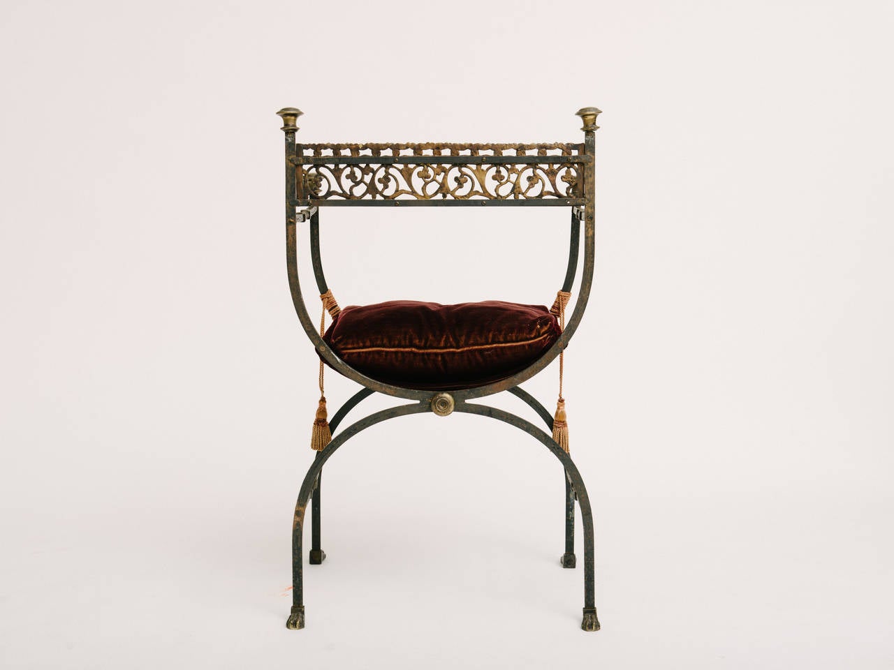 A Classic 1920s Bach/Segman style hand-forged wrought gilt iron Savonarola chair with beautiful cast bronze frieze, foot and finial details. Original claret mohair loose cushion with seat height of 21