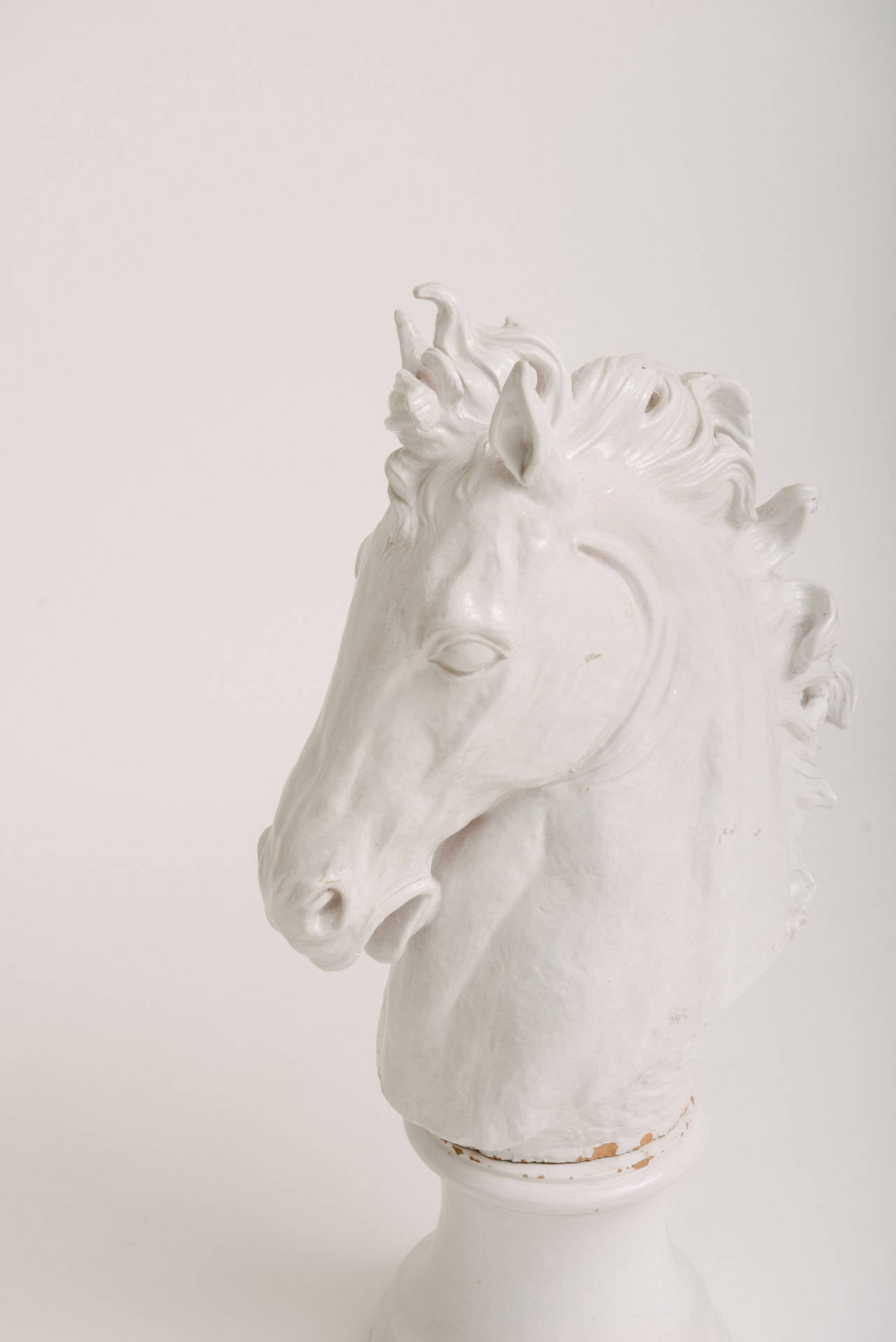 Stately Italian white glazed terra cotta horse head sculpture on stand. Small chipping of glaze where base meets sculpture. Easily touched up if desired.