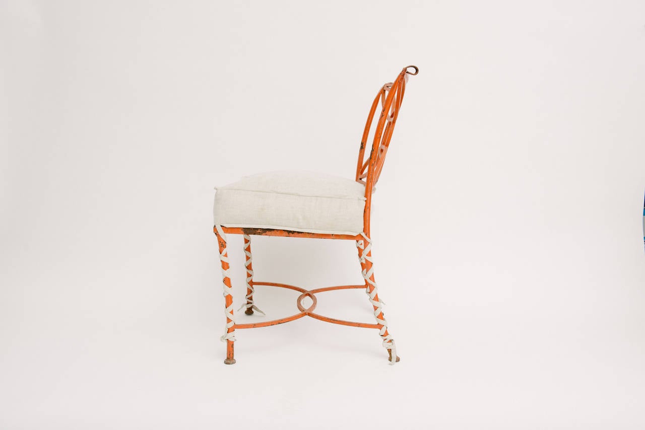 A delightful vintage orange painted iron occasional chair with upholstered oatmeal linen seat cushion with long ballet ties.