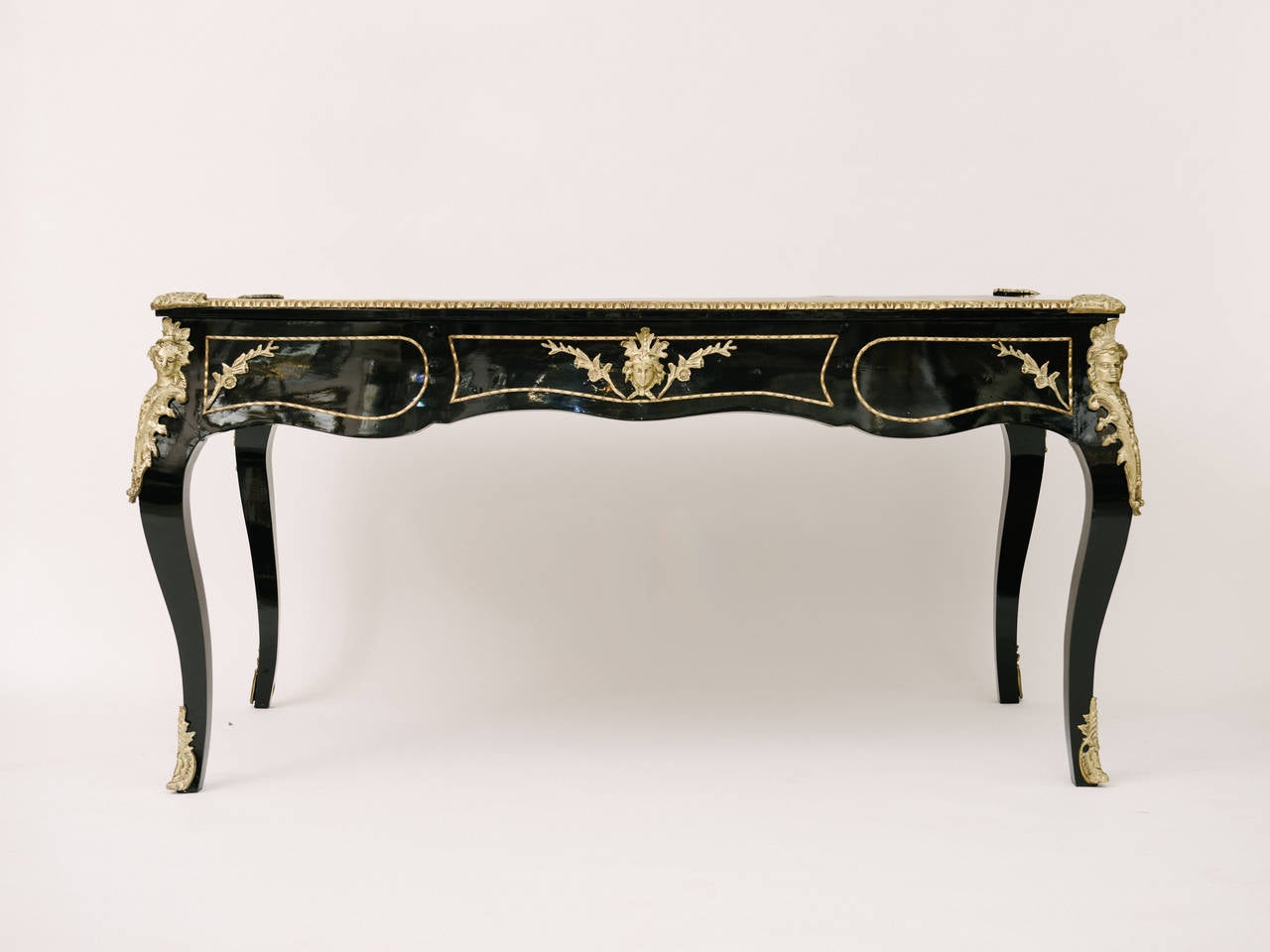 A high styled black lacquered Louis XV desk with bronze ormolu detailing and black leather inset top.