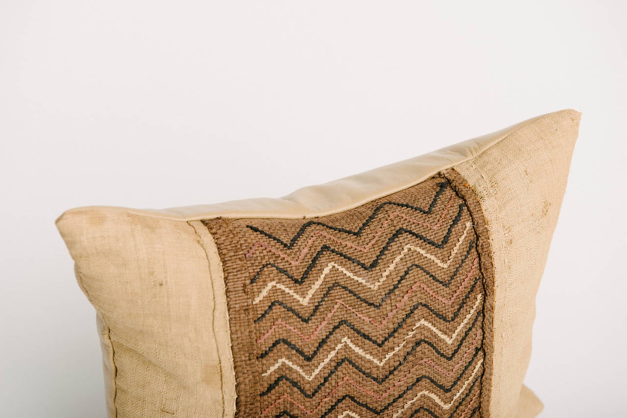 Vintage African raffia kuba woven textile throw pillow custom backed in buttery caramel leather and is feather down filled. Measures: 15 x 17.
