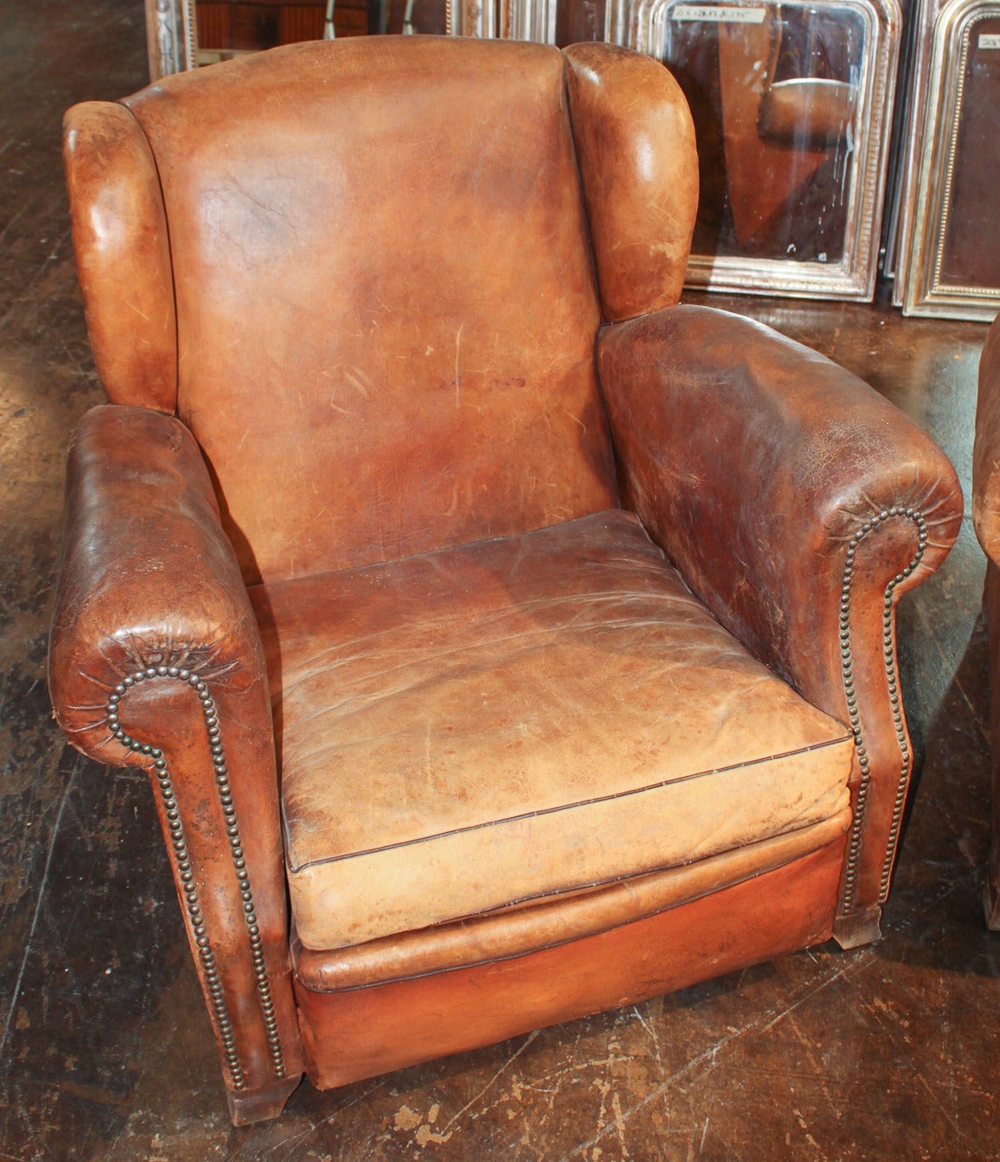 Superb pair of French leather club chairs in rare wingback style. Having larger scale than most, and with handsome aged brown leather. The leather upholstery is faded and consistent with age and wear; there are no tears or holes. Please view all