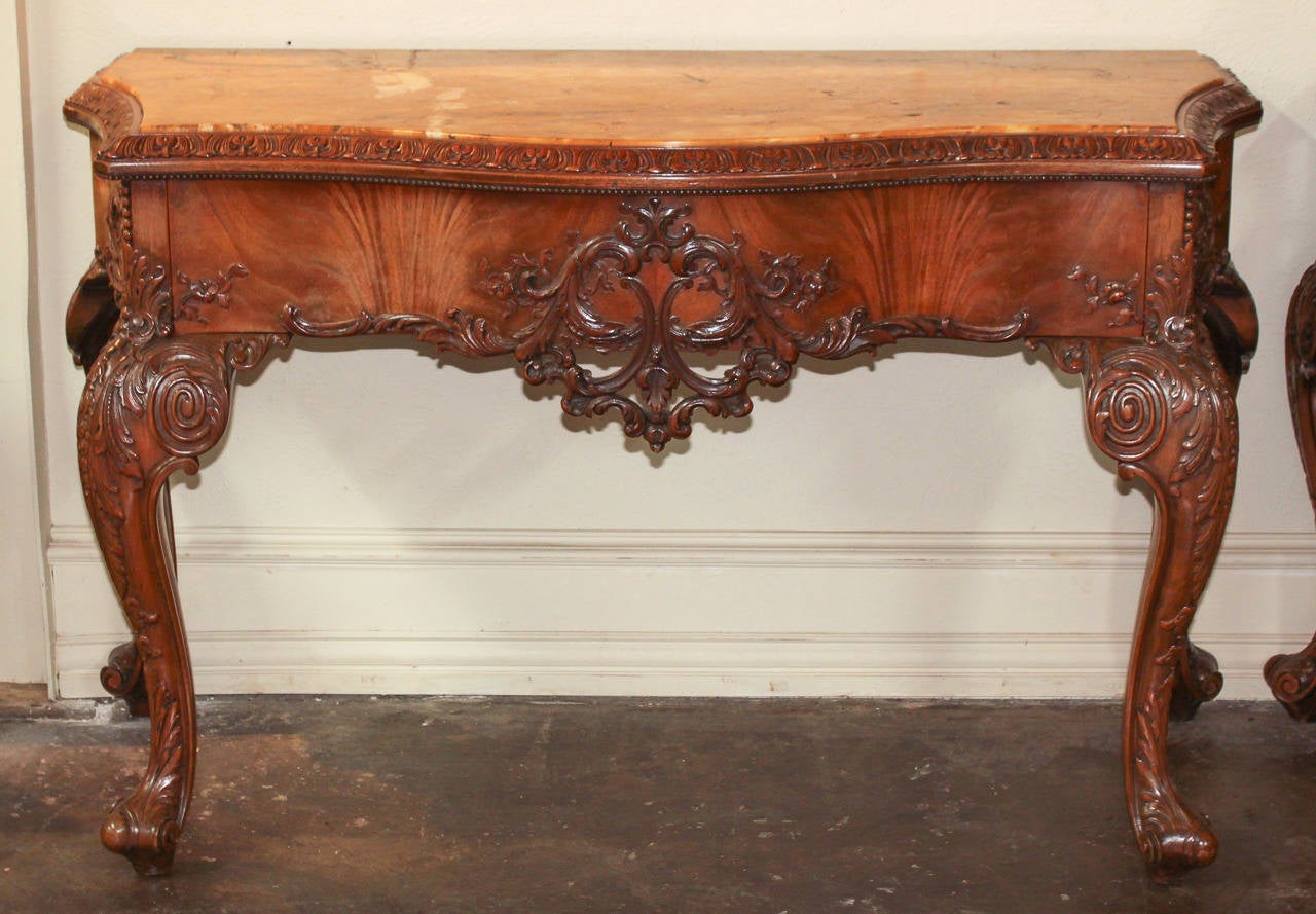 Magnificent pair of English mahogany console tables with Sienna marble tops. Elaborate hand carving adorns the shaped front apron and impressive cabriole legs. An absolutely beautiful finish combined excellent marble tops.
 