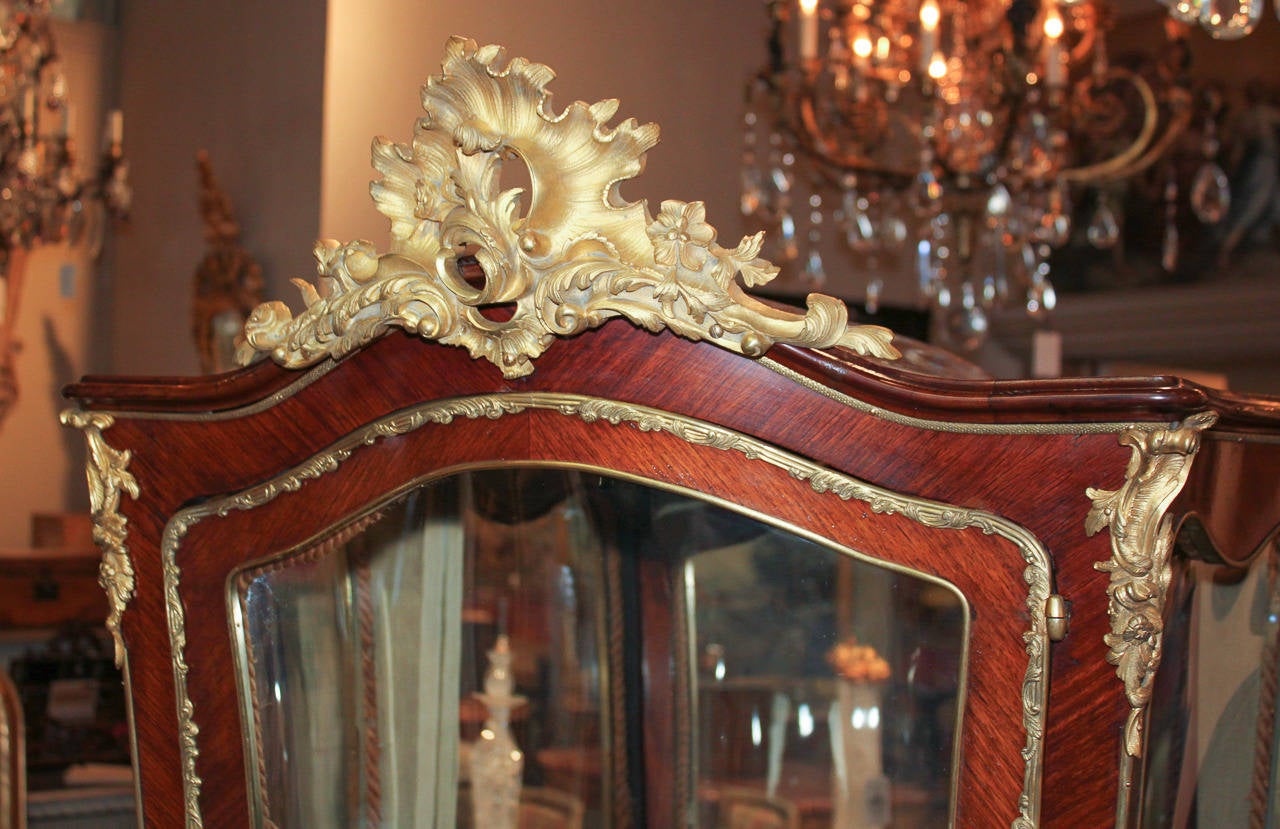 Magnificent French Louis XV gilt bronze mounted curio cabinet. Having shaped front, detailed and lustrous gilt bronze mounts in ornate foliate motifs, and adorned with courting scenes on lower portion. A Classic of heirloom quality and craftsmanship!