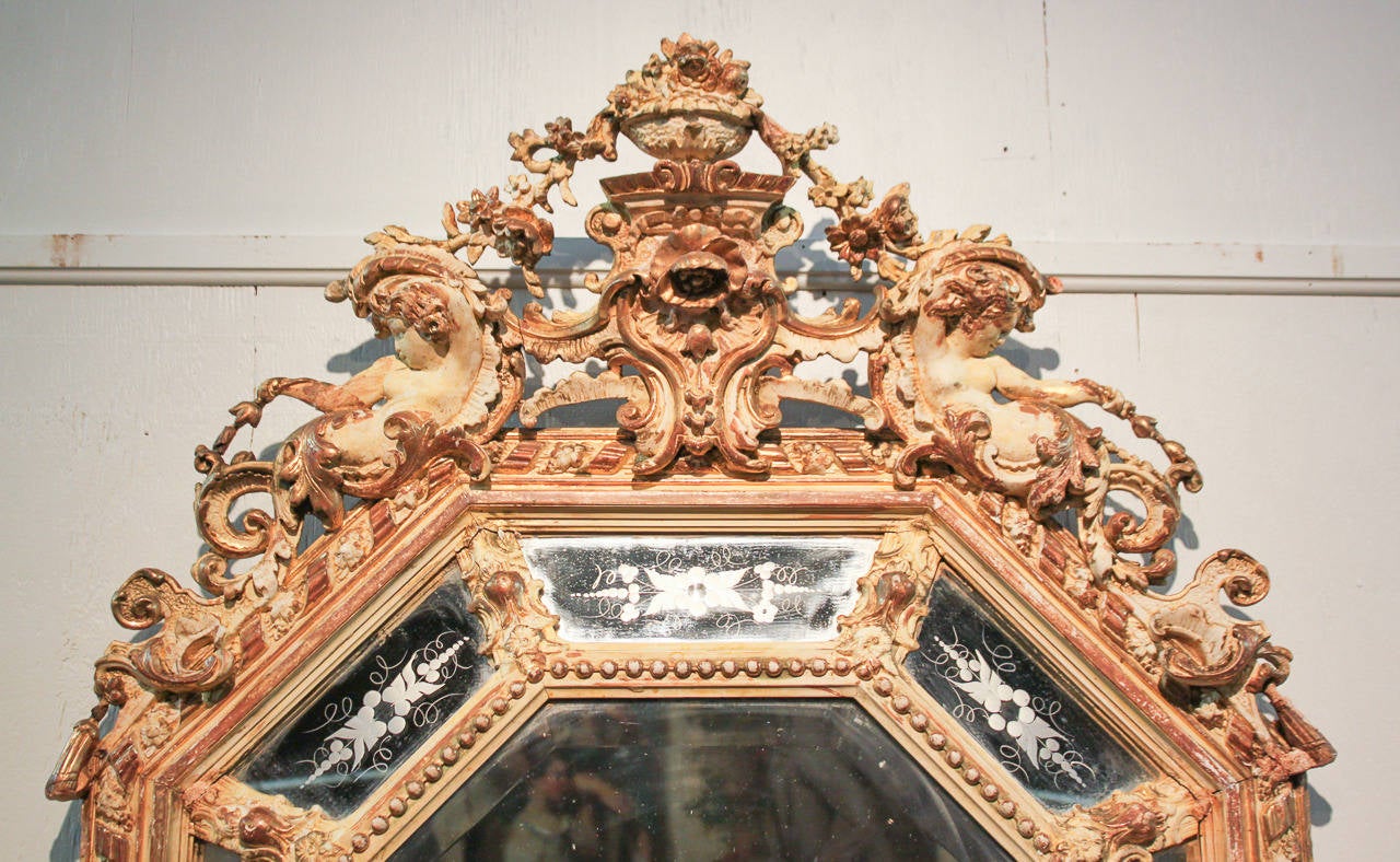 Splendido specchio francese Luigi XVI a cuscino ottagonale con bella finitura dorata e gesso. Ha un cartiglio a forma di cherubino intagliato a mano incredibilmente dettagliato, un vetro a specchio originale smussato e inciso e una bordatura intorno
