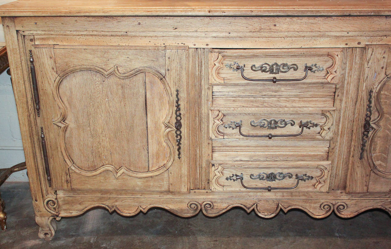 Lovely French oak 3-drawer, 2-door buffet with bleached finish.  Having bronze hardware and mounts, carved doors and apron, and resting on scroll feet.  The time worn patina offers rich character and charm.