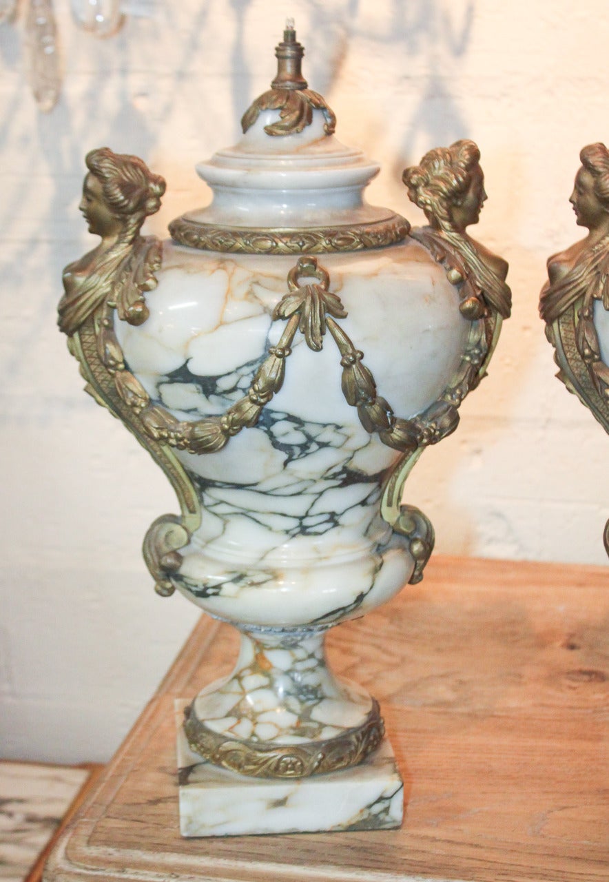 Magnificent pair of French Louis XV Arabescato marble and gilt bronze urns. Having lovely gilt bronze castings in acanthus leaf motif, female form figural handles, and beautiful veining in the marble.