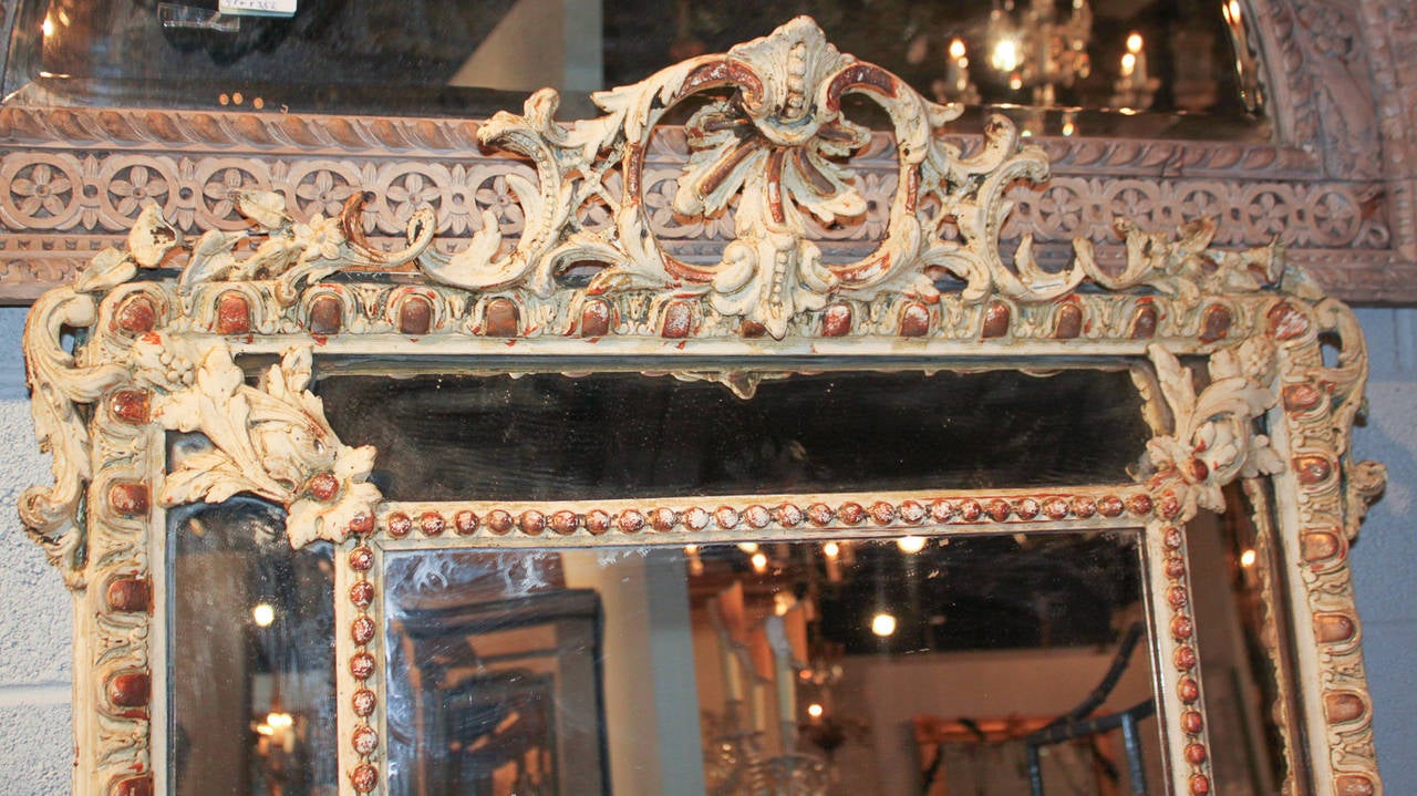 Fabulous French cushion mirror with antique gesso finish.  Having egg and dart outer frame with beaded center frame, and adorned with elaborately carved cartouche in acanthus leaf motif.