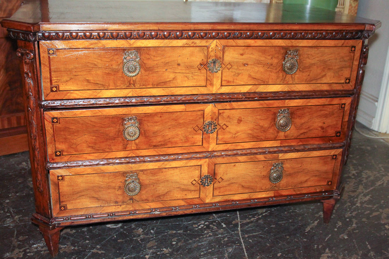 Handsome Italian neoclassical inlaid walnut three-drawer commode. Having lovely burl walnut bordered by satinwood and rosewood string inlays, bronze hardware, and carved rams head motif. Exhibiting a beautiful patina and clean lines.