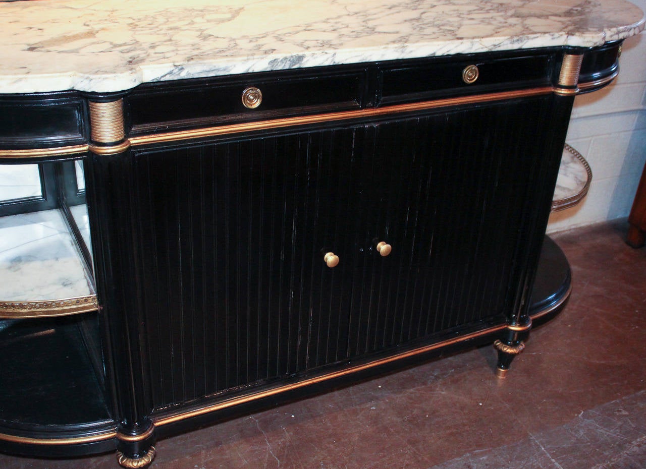 Sensational French black lacquered Directoire four-drawer buffet with Arabescato marble top. Having bow-sided marble shelves with brass reticulated gallery, giltwood trim, pivot drawers and fluted columnar supports and front doors. Exhibiting clean