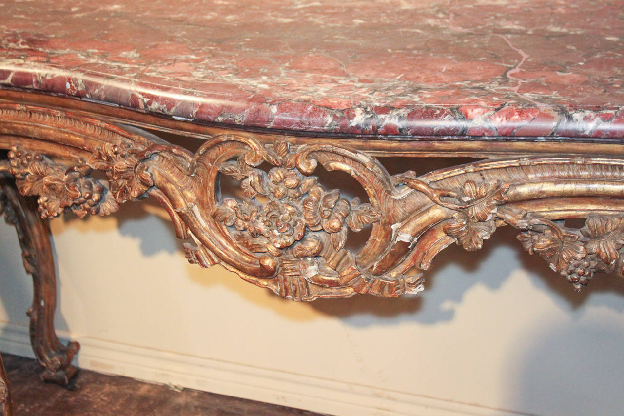 Beeindruckende großformatige französische Louis XV-Konsole aus handgeschnitztem Goldholz mit originaler Serpentinenplatte aus Villefranche de Conflent-Marmor. Mit prächtigen und aufwendigen Schnitzereien von Blumen und Weinreben Motiv über Fries und
